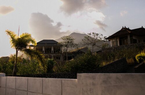 Scenic view of traditional villas set against a mountainous backdrop in Bali, surrounded by lush greenery. Ideal location for those looking to buy villas in Bali, combining natural beauty with the appeal of tranquil villa living.